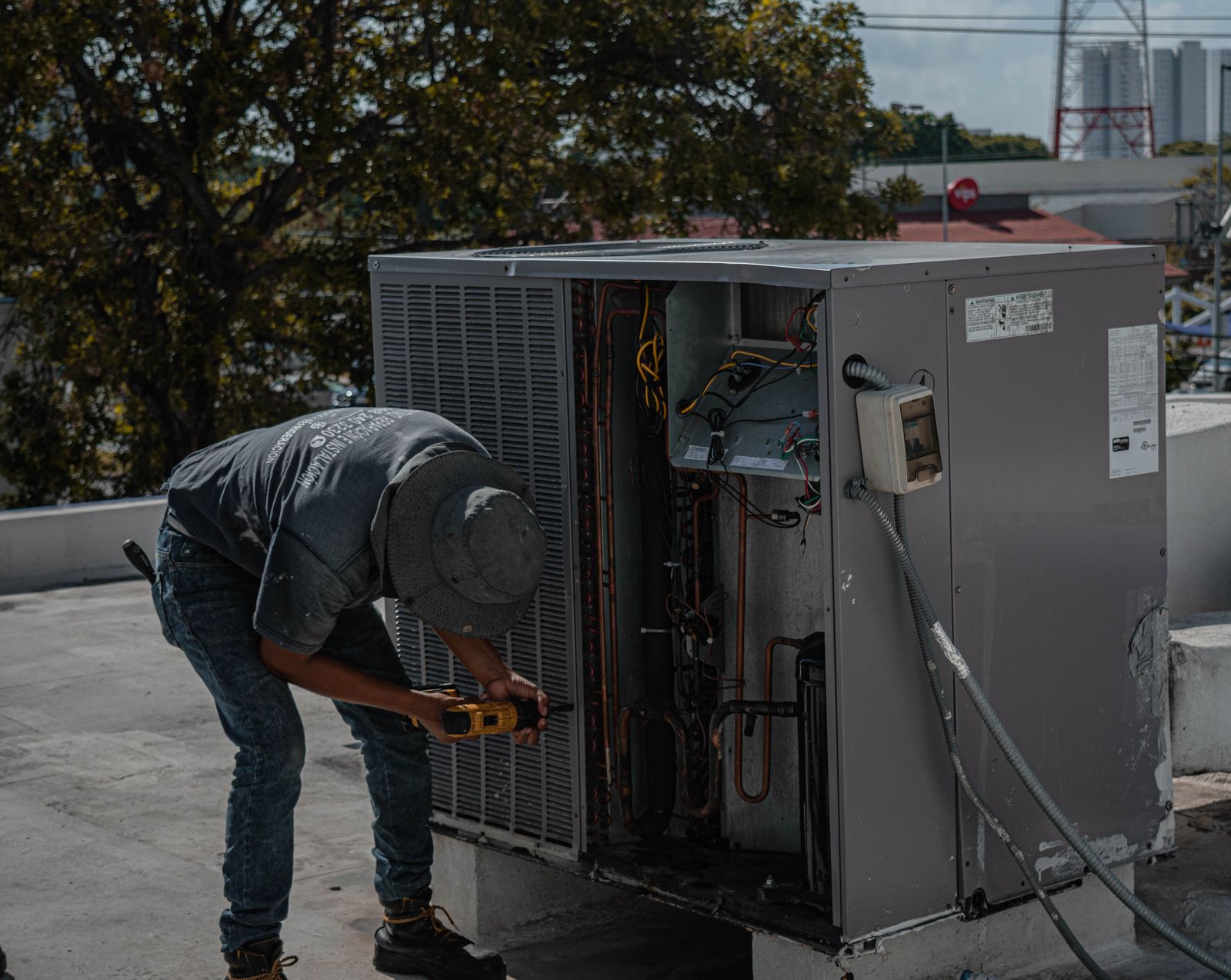 Technician repairing a rooftop air conditioning unit on a sunny day