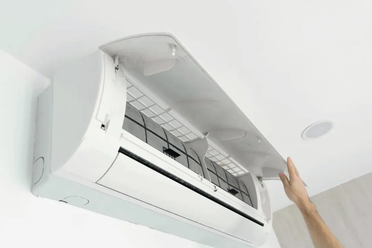 Hand opening the cover of a wall-mounted ductless air conditioner